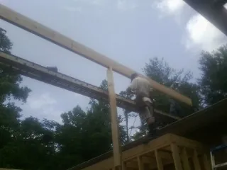 Carpenter setting a ridge beam over a new addition frame — Ice Dam Removal by Roofing Brothers in New Eagle