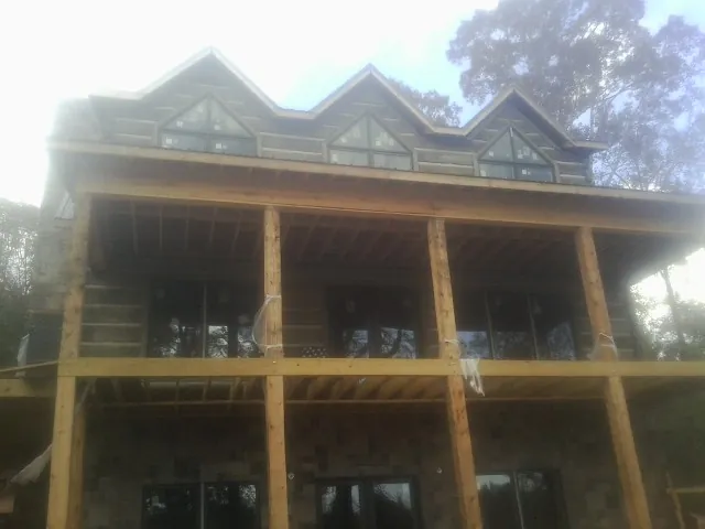 Dormers and porch framing on a large log home under construction — Roof Coating work by our crew in New Eagle