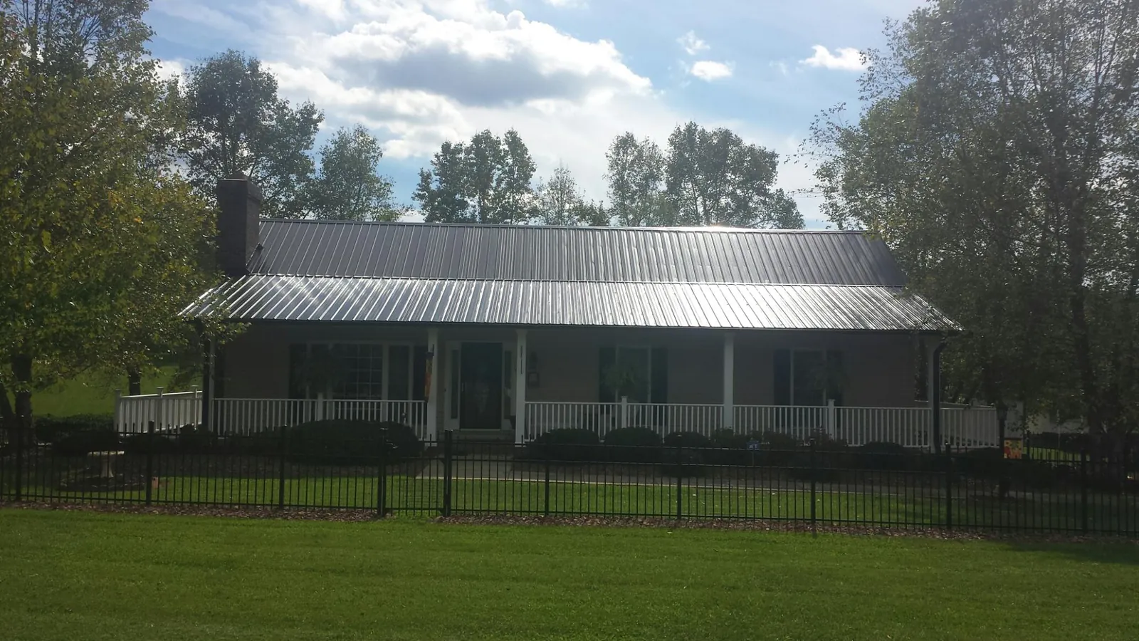 Gray metal roof on a brick ranch with a full width front porch — Gutter Guard Installation work by our crew in New Eagle