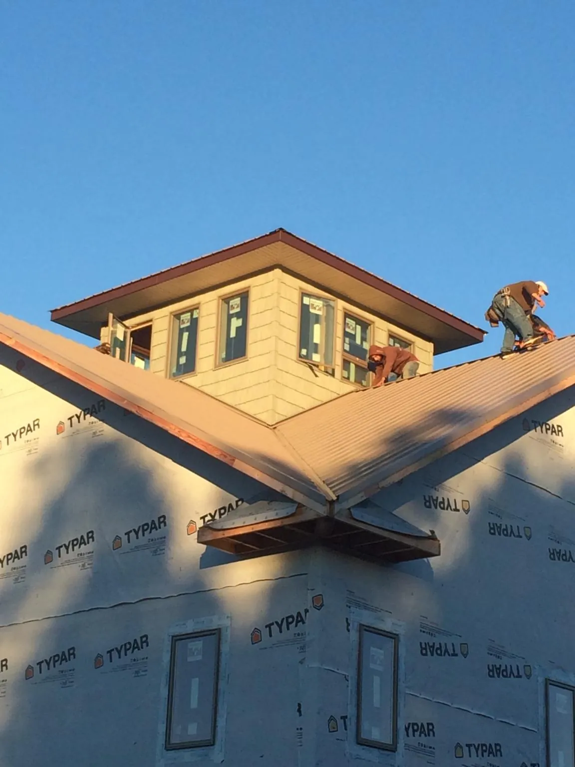 Roofers working around a rooftop cupola on a new metal roof at sunset — Roof Waterproofing in New Eagle by Roofing Brothers